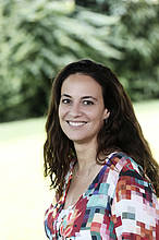 Betina Johannes ist für die Buchhaltung des Familienforums zuständig. Sie hat lange braune Haare, trägt eine bunte Bluse und lächelt.