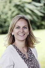 Friederike Wentingmann koordiniert die Einzelveranstaltungen des Familienforums und kümmert sich um die Öffentlichkeitsarbeit. Sie hat lange blonde Haare, trägt eine braune Bluse mit weißen Punkten unter einer beigen Strickjacke. Friederike lächelt.